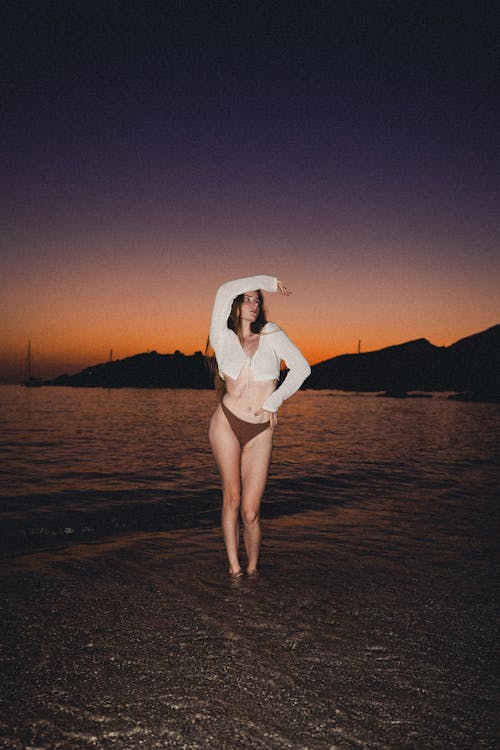 Model Posing with Arm Raised on Sea Shore at Sunset