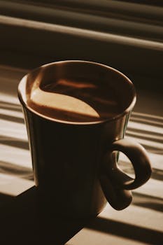 A cozy cup of coffee in soft, warm sunlight creating tranquil morning vibes.