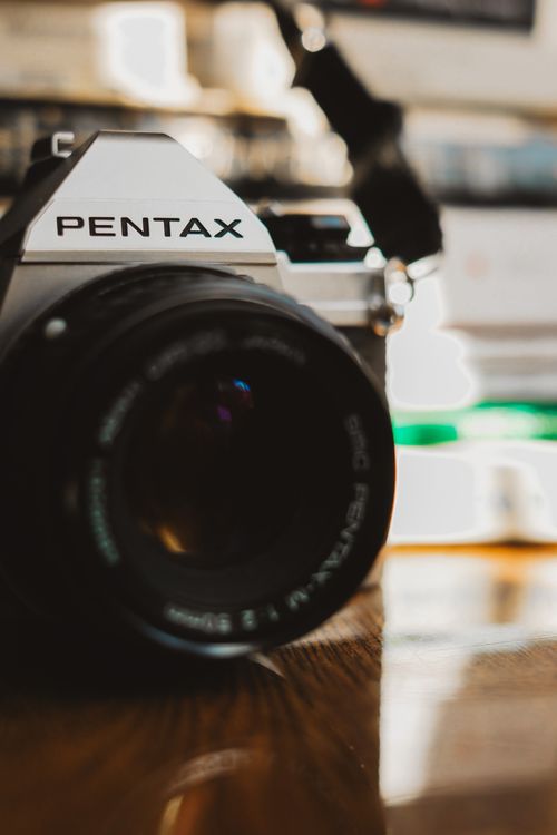 Free A close-up shot of a classic film camera lens on a wooden table. Stock Photo