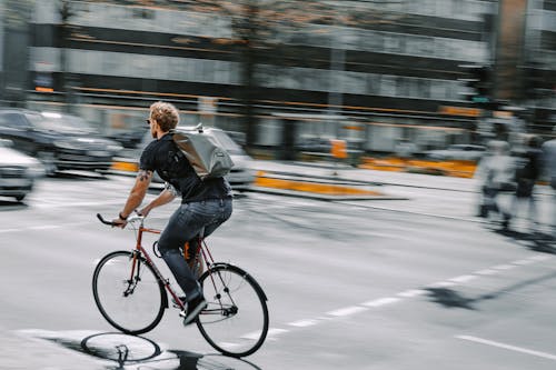 Man Riding Bike on Street in City