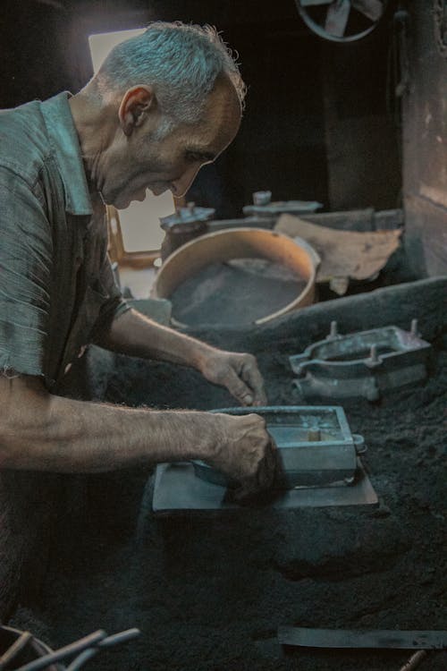 Elderly Man Working with Metal in a Workshop 