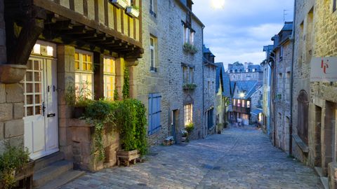 Explore the illuminated cobblestone streets of historic Dinan, Brittany at dusk.
