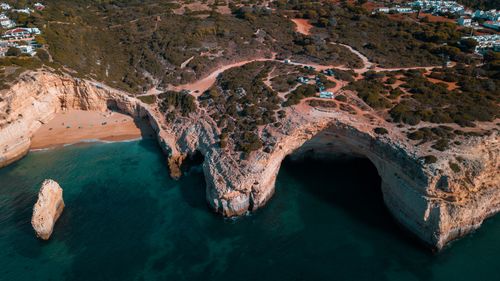 Free Stunning aerial view of rocky coastal cliffs with clear blue sea and sandy beach in a natural landscape. Stock Photo