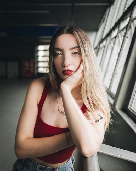Portrait of a fashionable young woman in a red top posing indoors, exuding confidence and style.