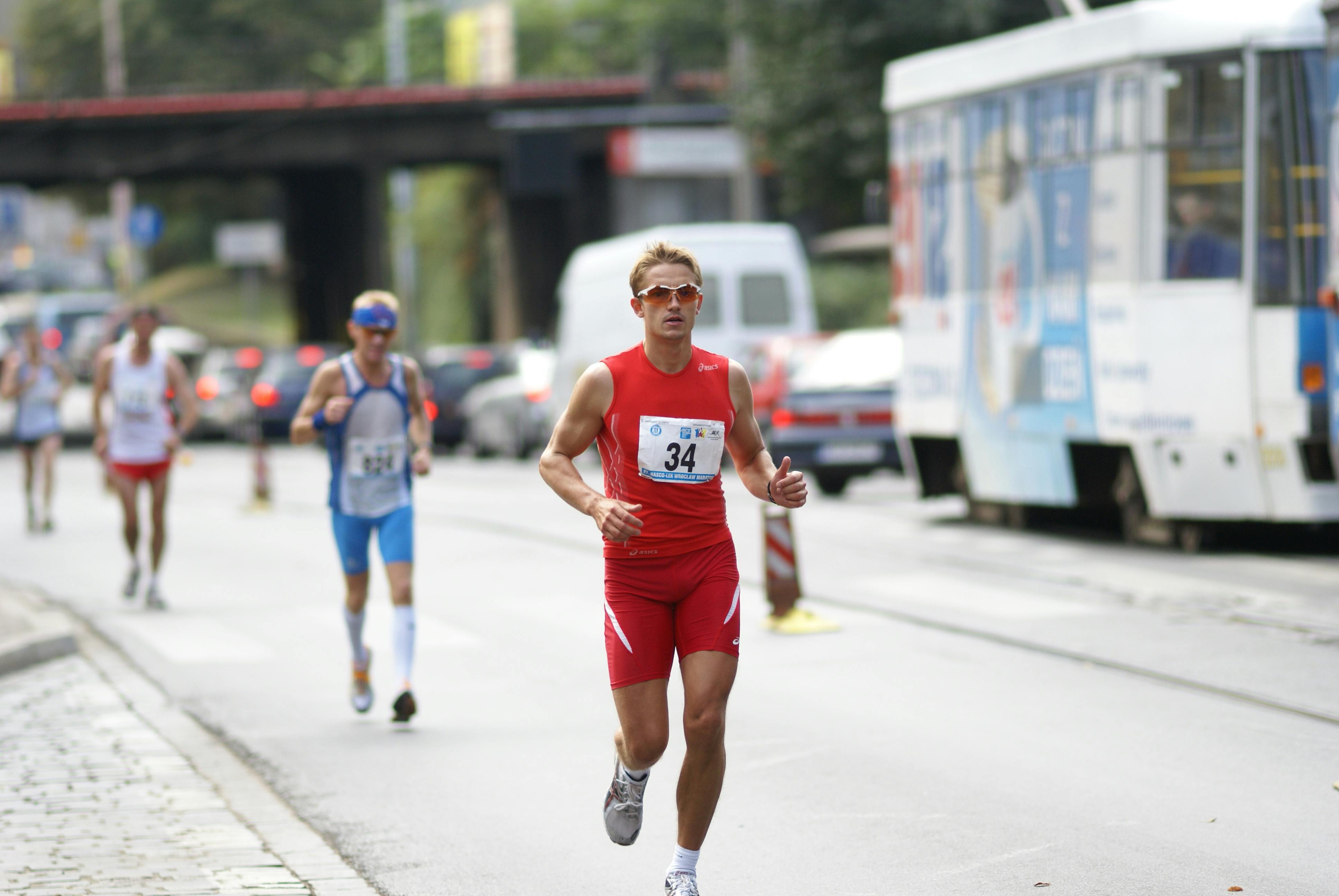 Person tying shoelaces, looking determined, before a run outdoors in a park.
