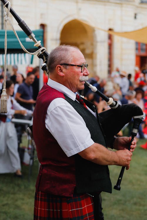Man in Traditional Clothing Playing Bagpipes