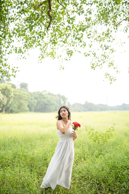 ayakta, Beyaz elbise, Çiçekler içeren Ücretsiz stok fotoğraf