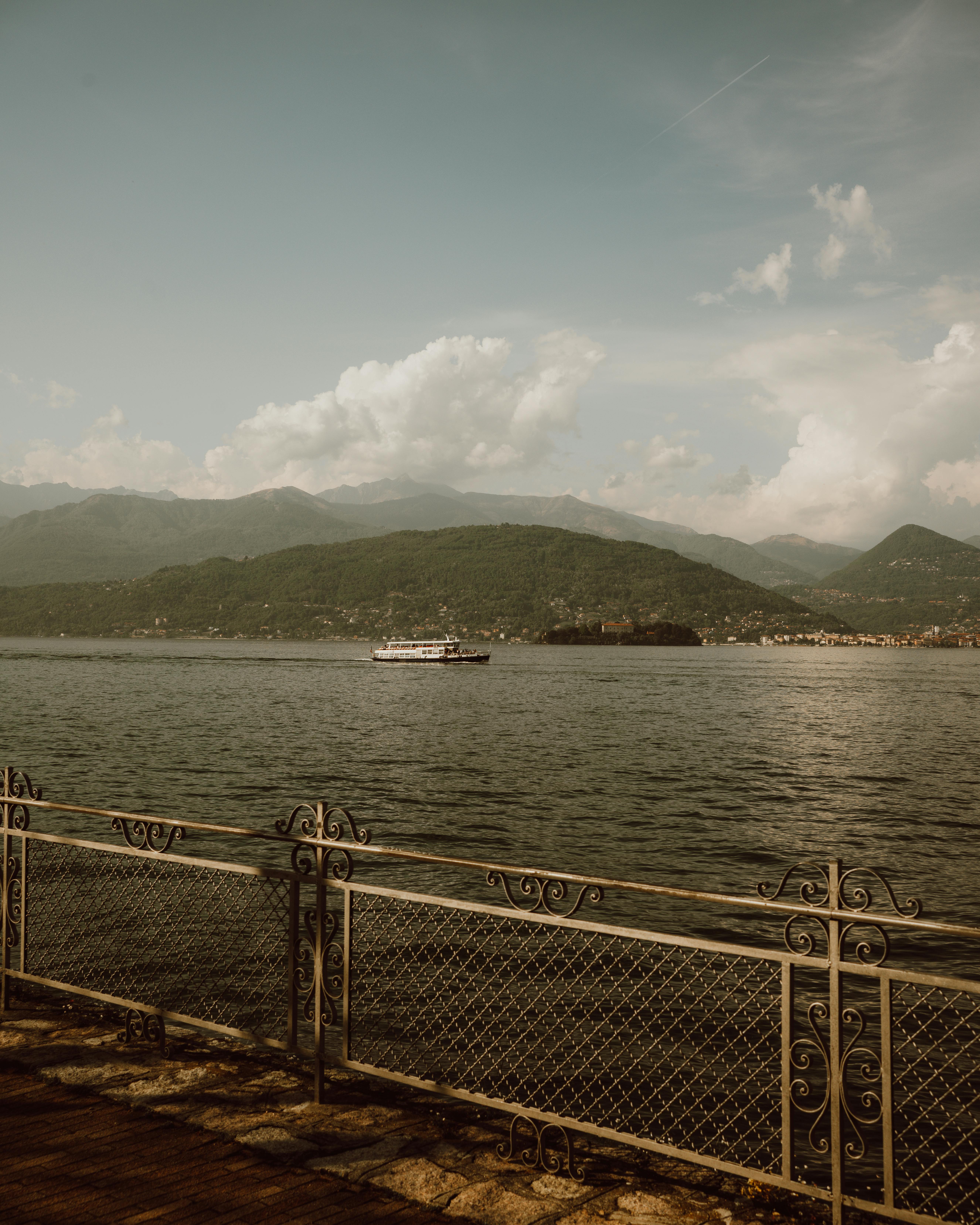 Serene view of Lake Maggiore from Stresa, Italy, showcasing mountains and a ferry.
