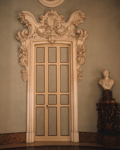 View of a Doorway with Carved Details on the Frame and a Sculpture