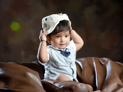 A Little Boy Putting on a Hat