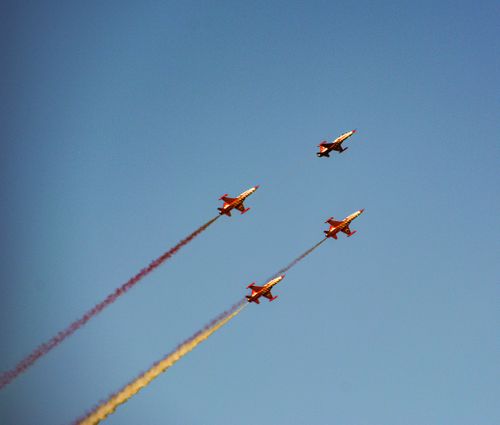 Free Four aerobatic aircraft creating colorful trails while performing in a clear blue sky. Stock Photo