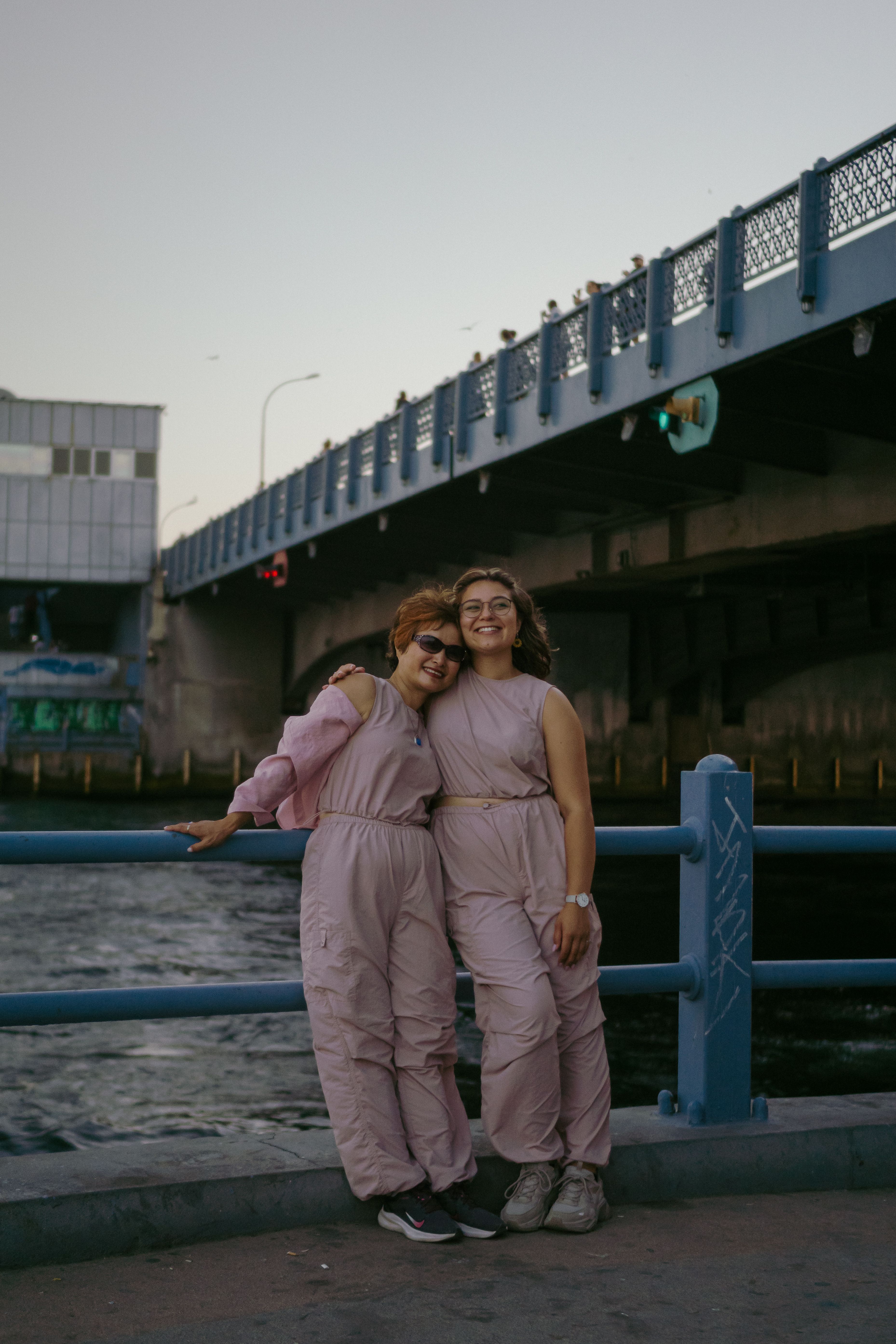 Smiling Women Standing by Railing under Bridge · Free Stock Photo