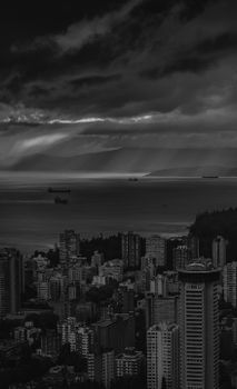 Black and white aerial view of Vancouver skyline under dramatic clouds.