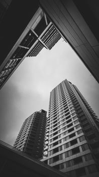 Low-angle view of modern skyscrapers, dramatic in black and white, showcasing urban architecture.