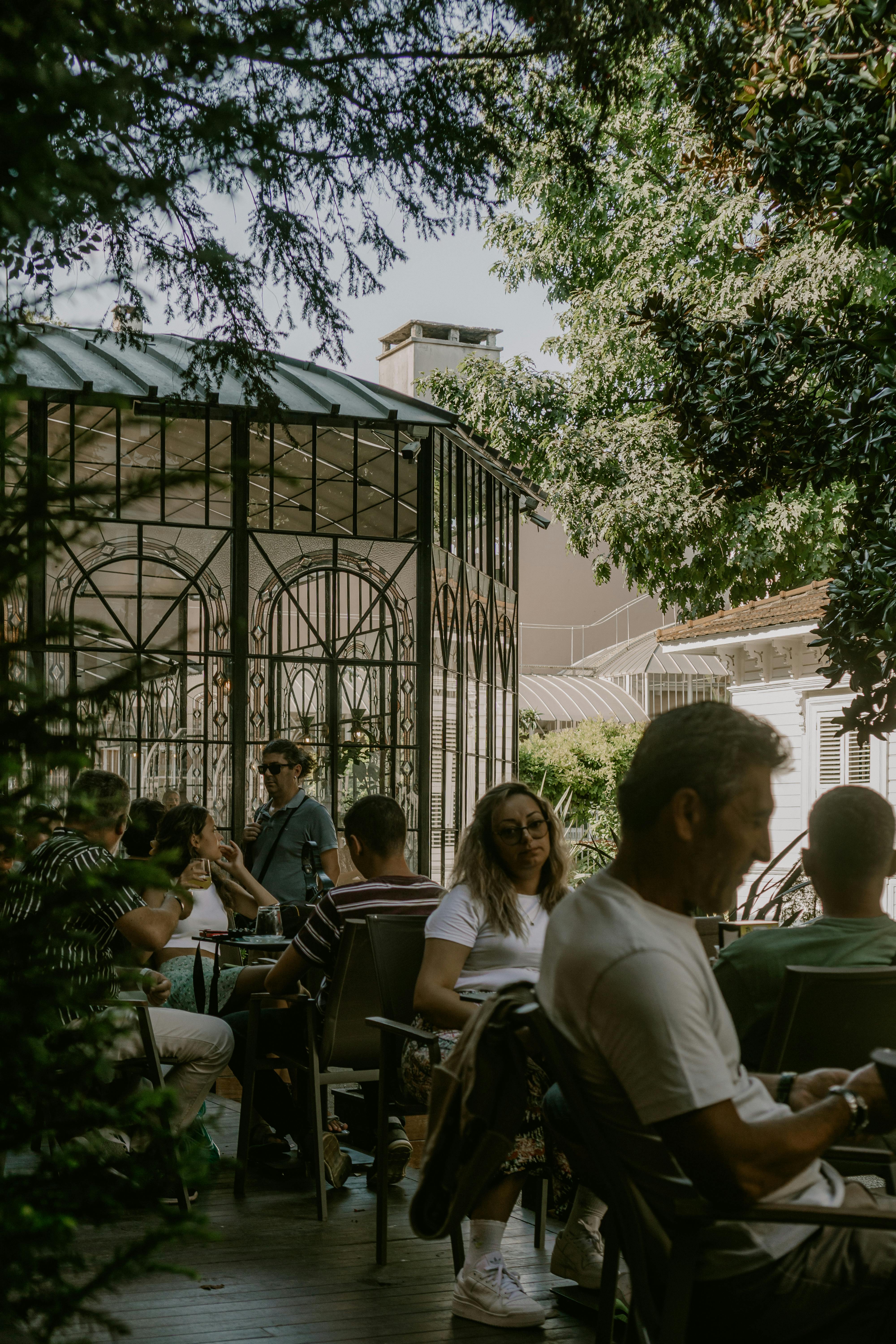 People enjoying a meal in an outdoor garden restaurant with greenery.
