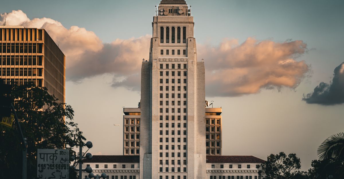 Iconic Los Angeles City Hall illuminated by a dramatic sky at sunset, showcasing urban architecture.