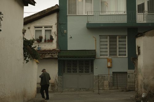 Free An elderly man walks through a quiet suburban alley beside residential buildings. Stock Photo