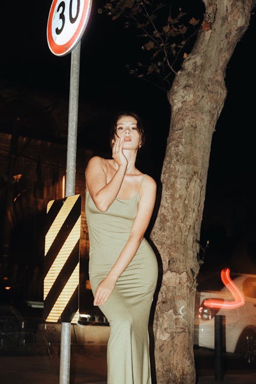 Woman Posing Next to a Tree at Night