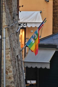 Colorful rainbow flag hangs by a building wall, symbolizing pride and diversity.
