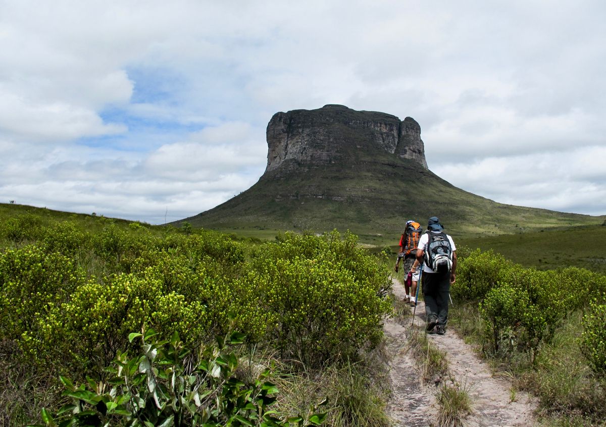 Hikers walking towards iconic rock formation in Chapada Diamantina, Brazil.