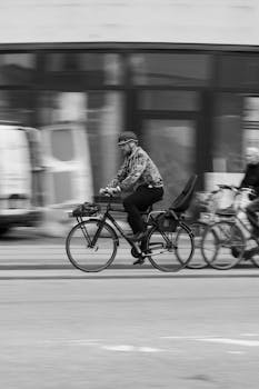 Black and white photo of a cyclist in motion on Copenhagen streets, capturing urban life.
