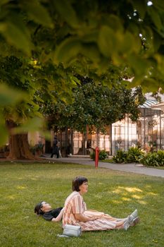 Two women enjoying a sunny day in a city park, relaxing on the grass.