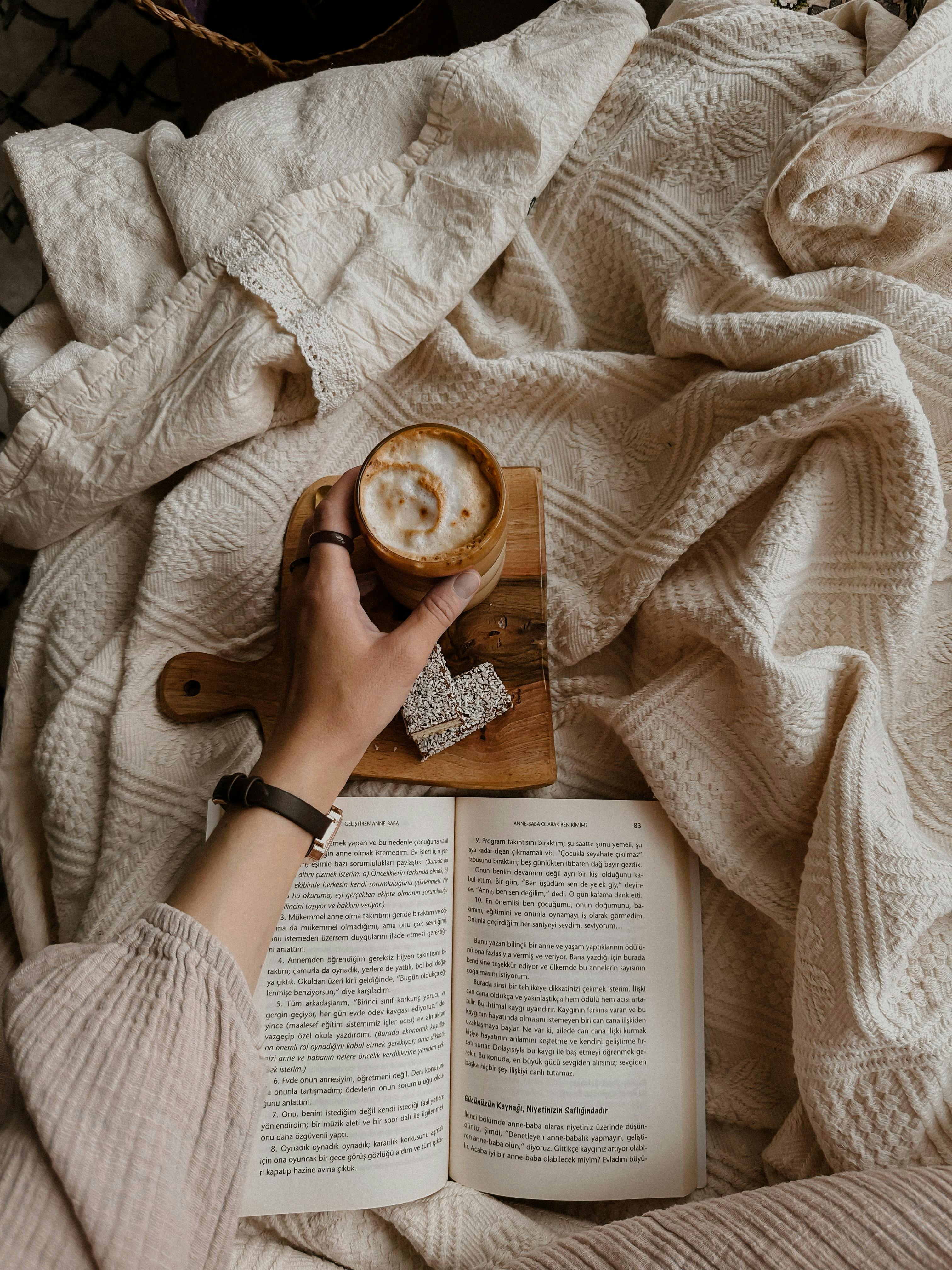 Enjoy a relaxing moment with a book and coffee on a soft blanket.