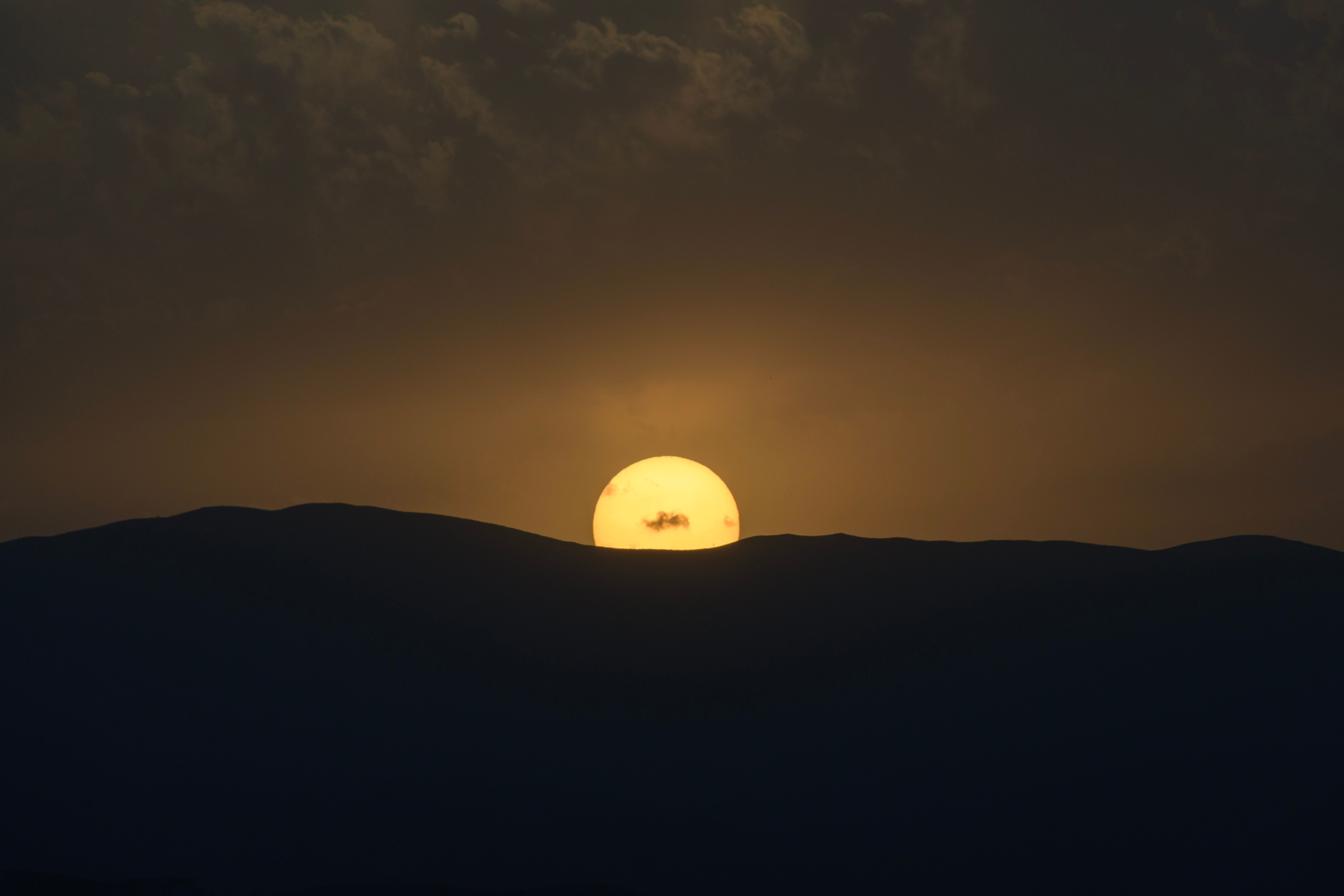 The sun is setting over a mountain range · Free Stock Photo