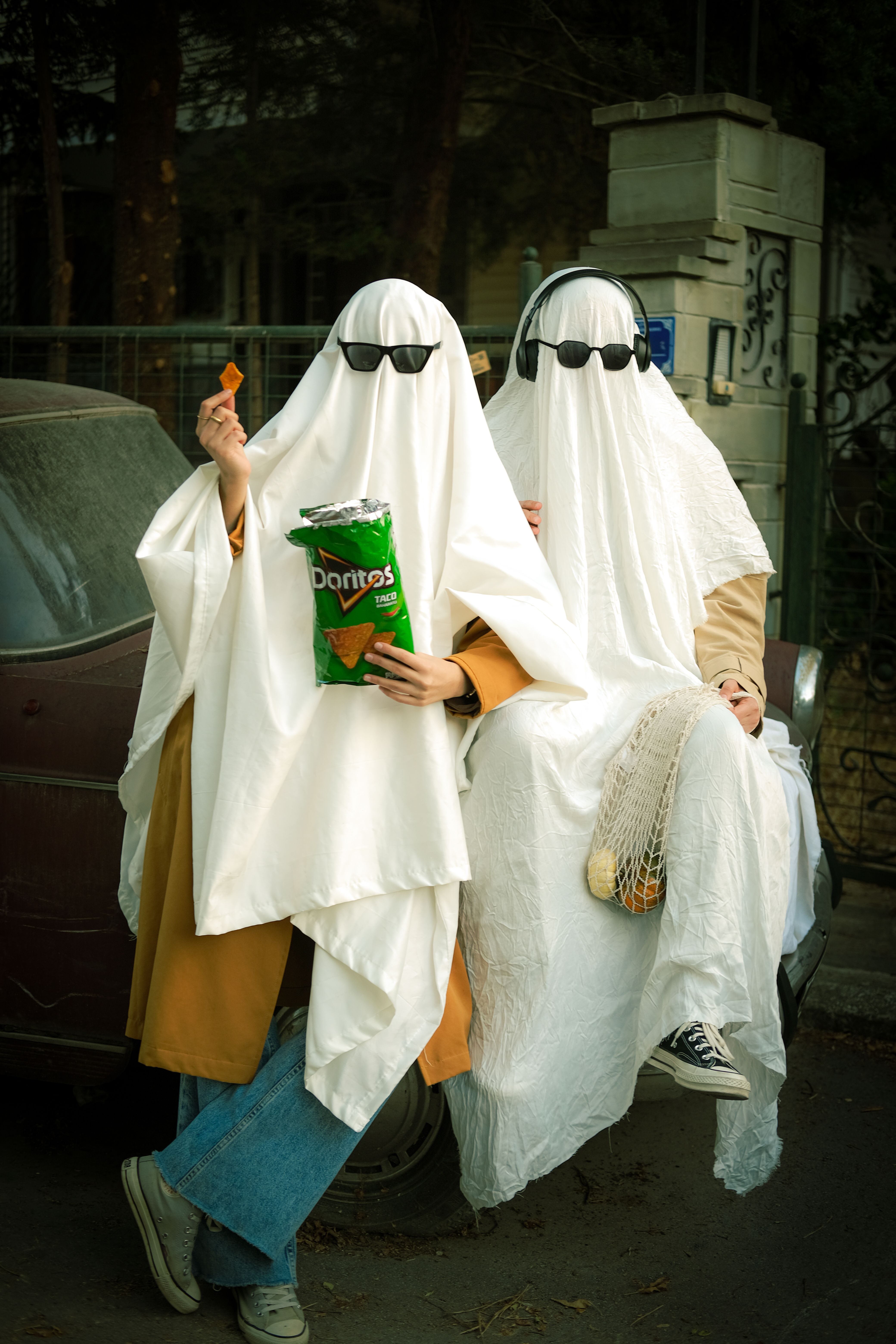 Two people in ghost costumes enjoying snacks, embodying a humorous Halloween vibe.
