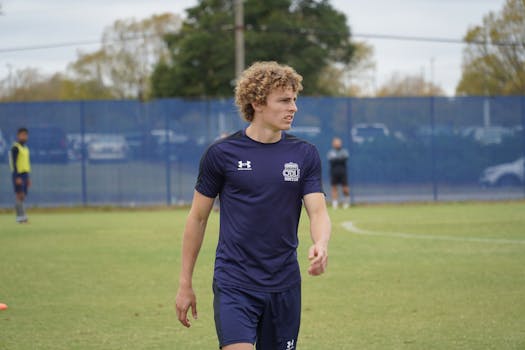 Young male soccer player walking on an outdoor field during practice.