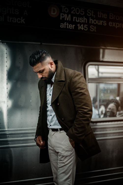 Free Stylish man in brown coat and white shirt poses at urban train station platform. Stock Photo