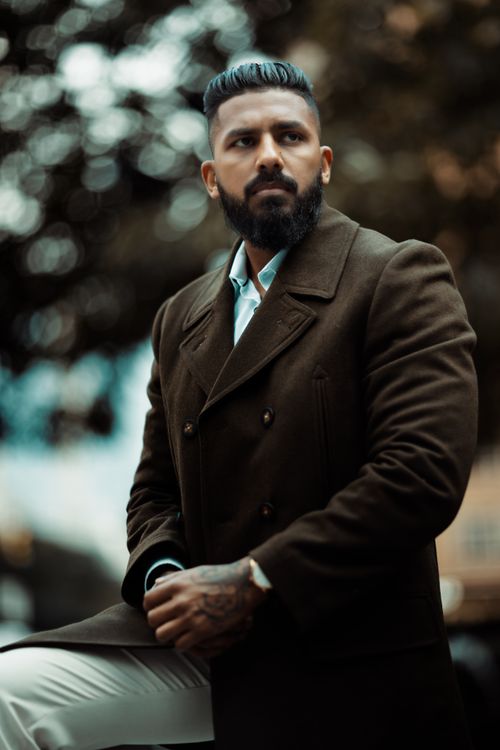 Free Fashionable man with beard and mustache posing in a brown coat outdoors. Stock Photo