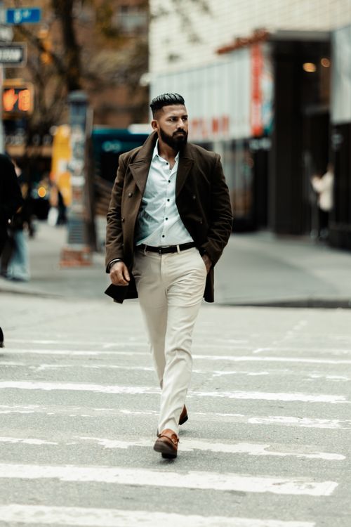 Free Stylish man with a beard walking across a city crosswalk, showcasing modern street fashion attire. Stock Photo