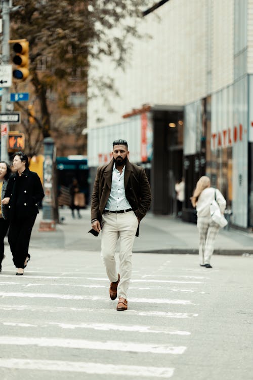 Man Wearing Brown Overcoat and White Shirt Walking Across the Street