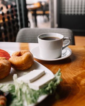 Warm and inviting breakfast setting with coffee and pastries at a cafe table, perfect for a relaxed morning.
