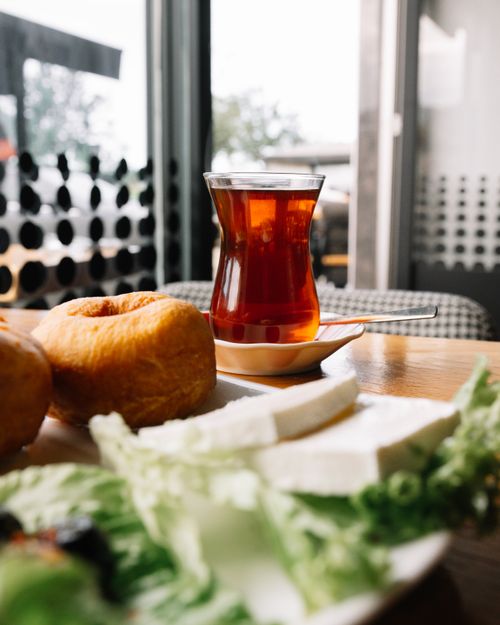 Free Traditional Turkish breakfast arrangement with tea, pastries, cheese, and salad on a wooden table. Stock Photo
