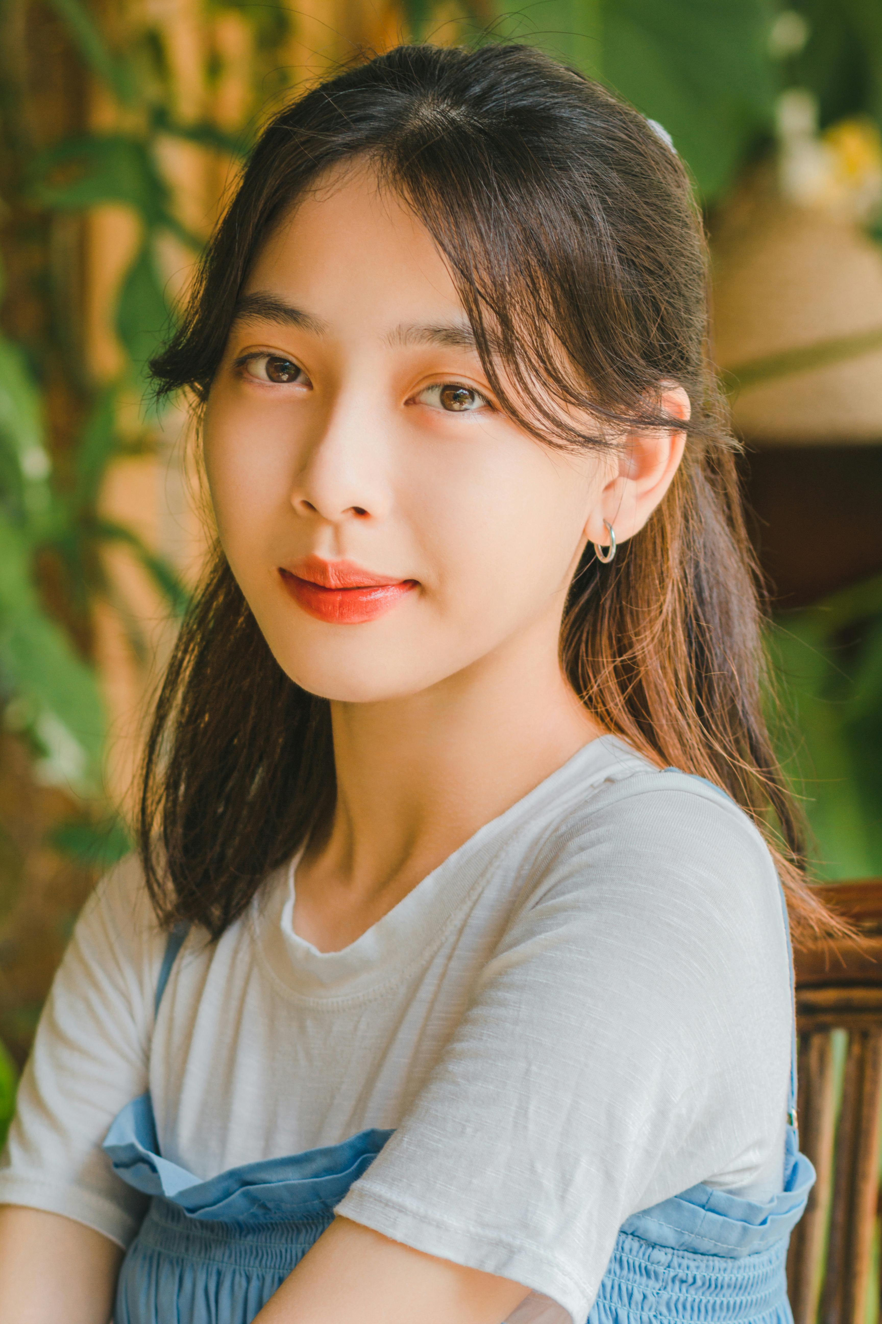 Charming portrait of a young woman smiling softly while seated outdoors.
