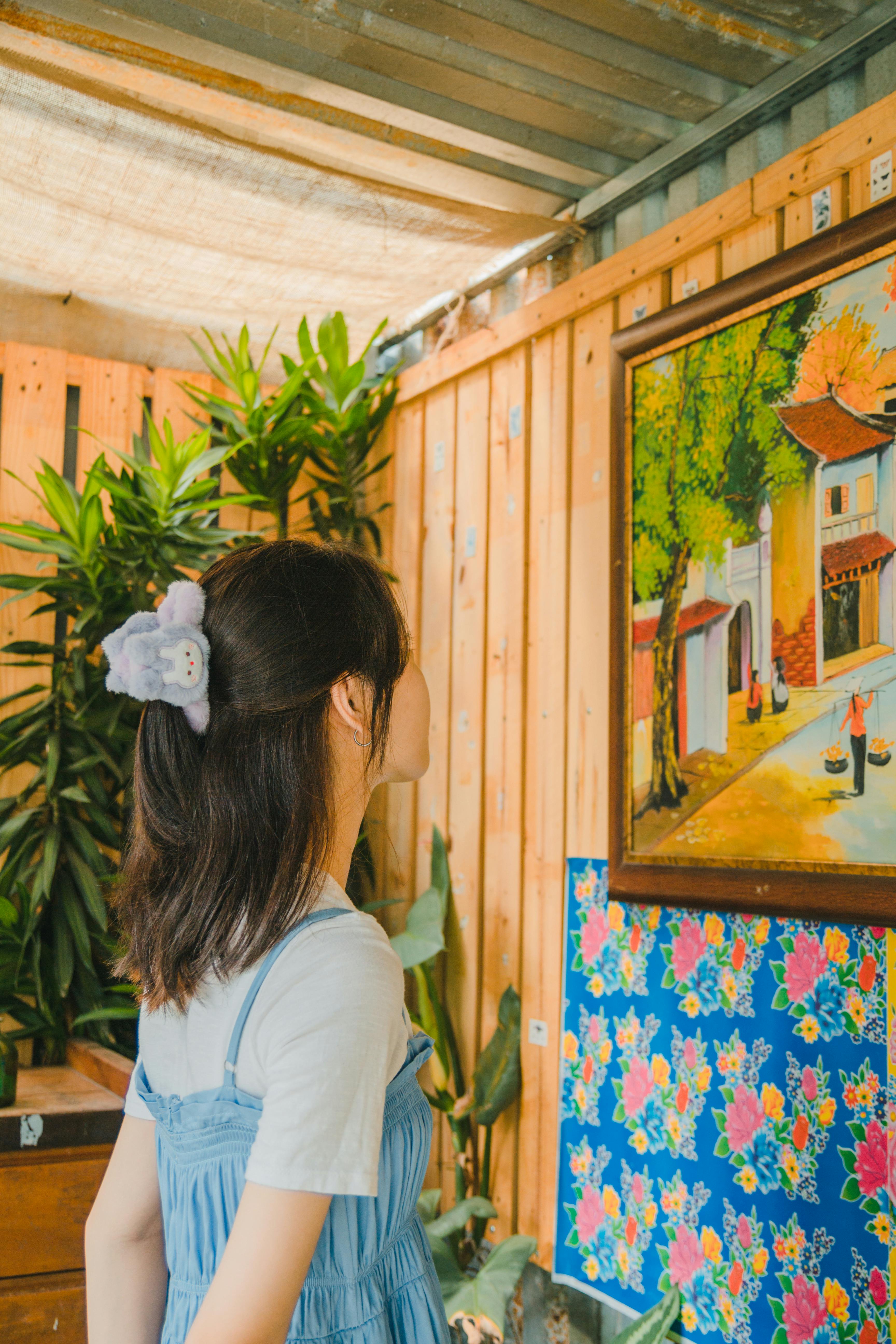 Woman in a cozy room gazing at vibrant wall painting. Indoor art contemplation.