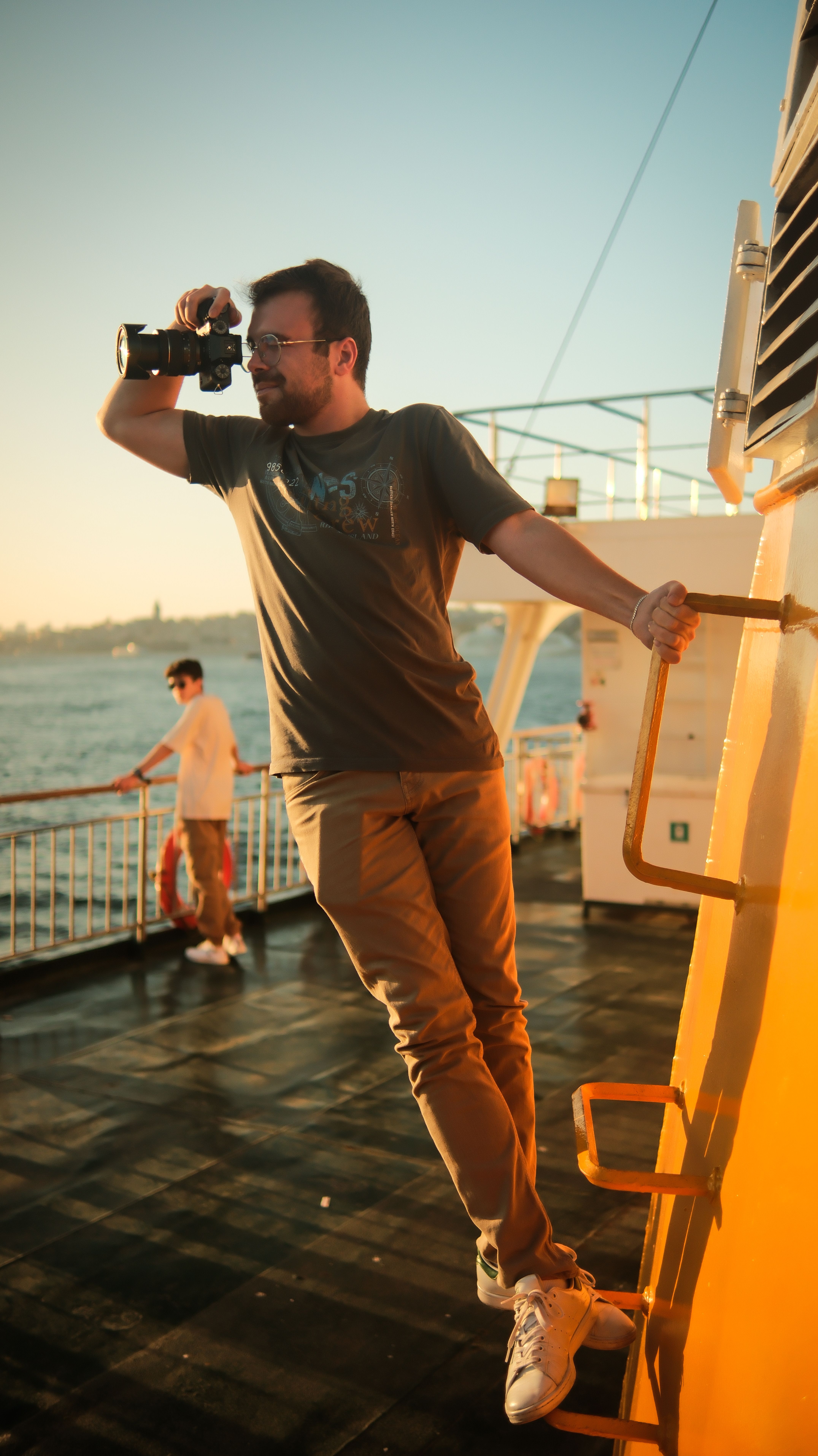A man taking a photo at sunrise on a ship deck, capturing the scenic view.