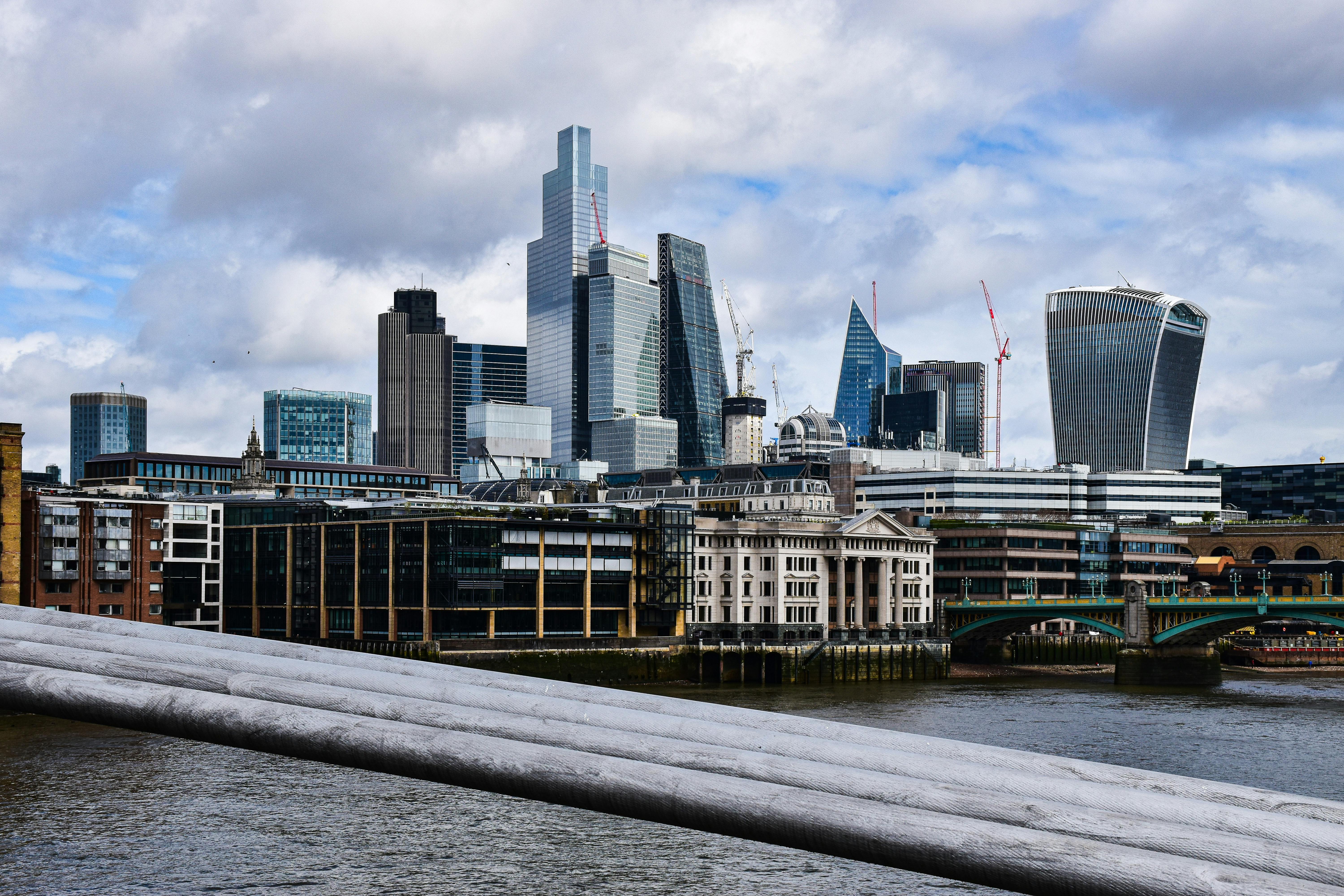 Londra şehir manzarasına karşı modern bir ofis ortamında çalışan mutlu bir profesyonel, İngiltere'de aile birleşimi ve kariyer gelişimini simgeliyor.