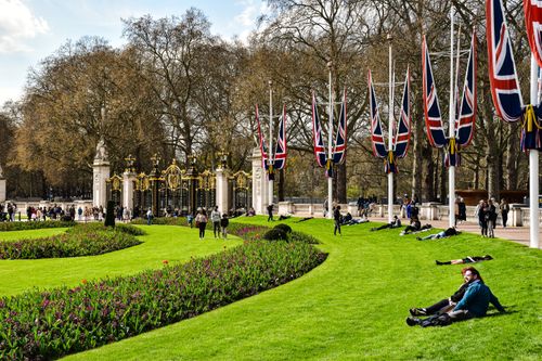Free Tourists enjoy a sunny day at the gardens near Buckingham Palace, London. Stock Photo