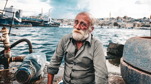 Elderly Man with a Gray Beard Sitting on the Shore in Istanbul, Turkey 