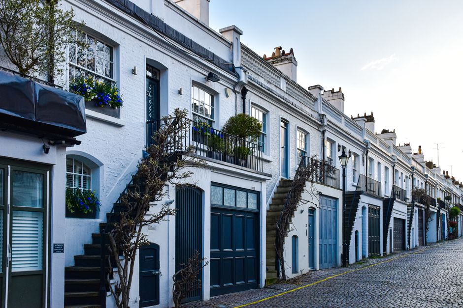 Picturesque view of traditional London mews with elegant blue doors and windows, showcasing unique architecture.