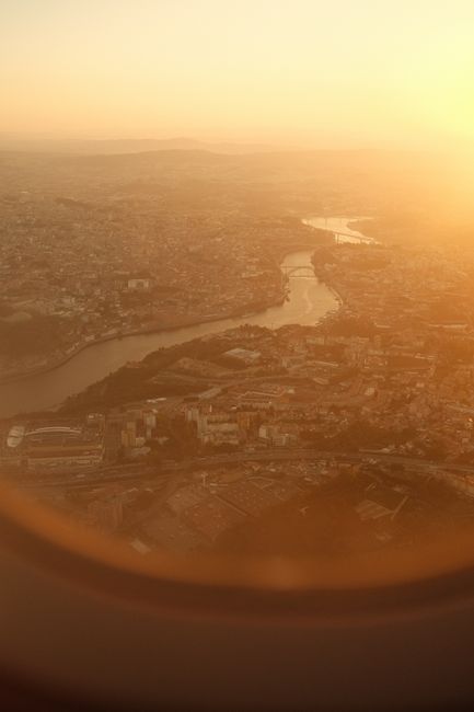 Stunning aerial cityscape view captured from an airplane window during a golden sunset, highlighting winding river.