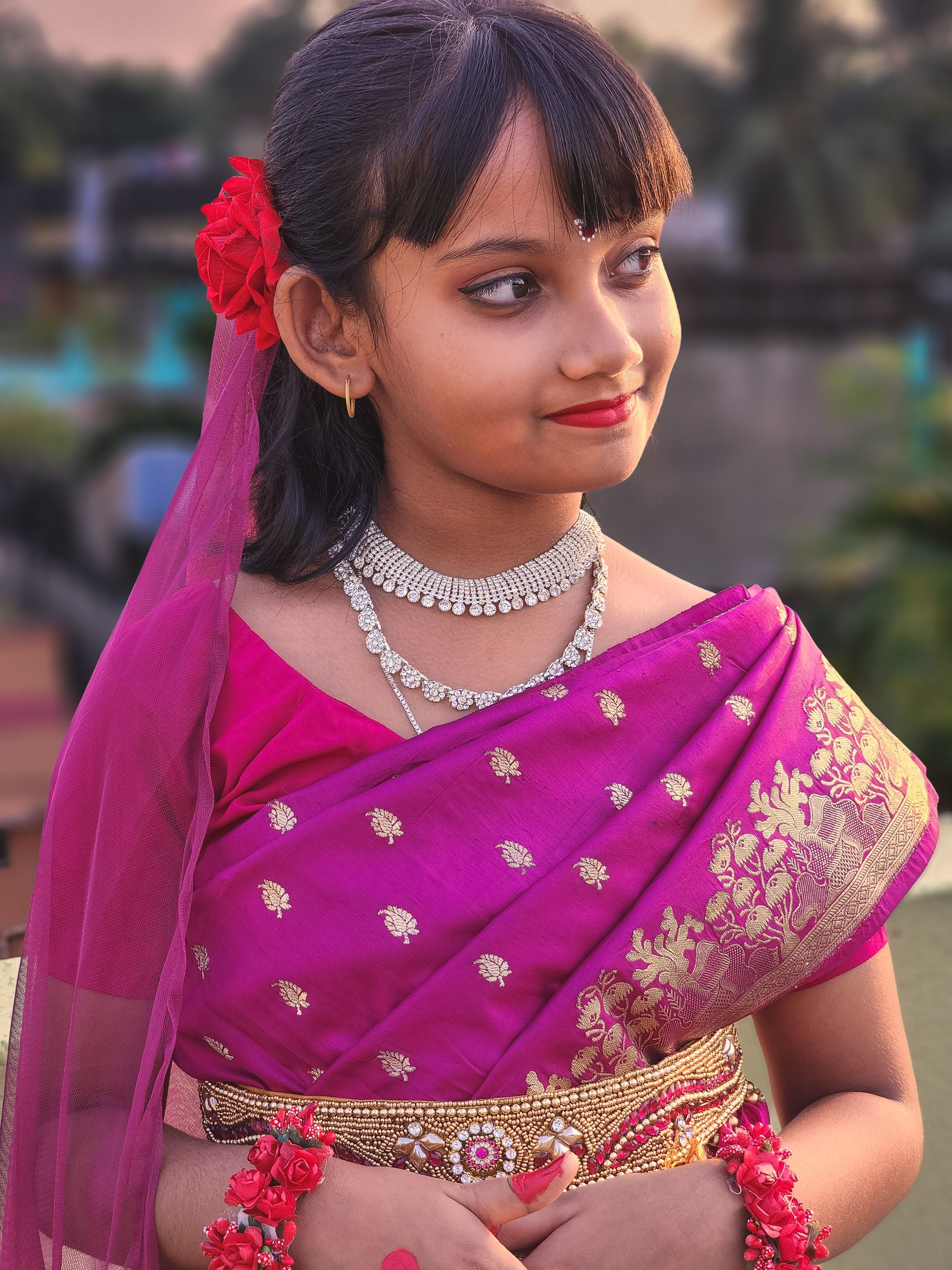 A young girl wearing a vibrant purple sari and traditional jewelry, embodying Indian culture.