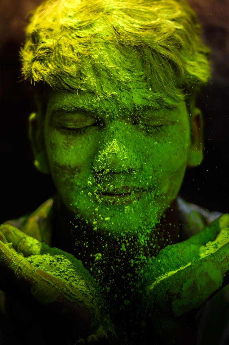 A Person's Face Covered With Green Powder 