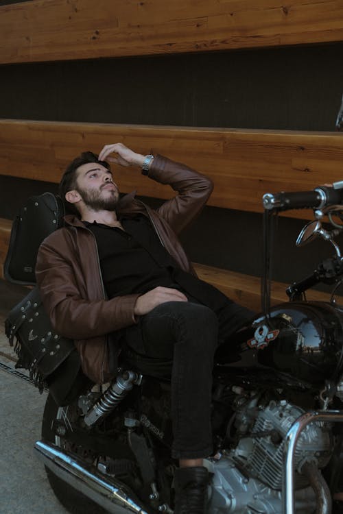 Man in Jacket Lying Down on Motorbike