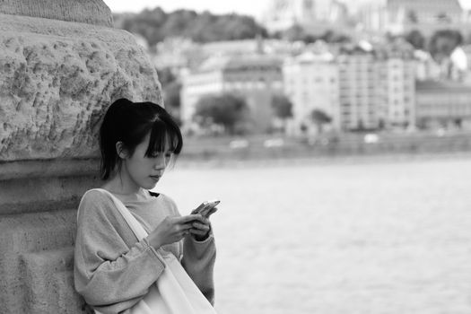 A woman using her smartphone by the Danube River in Budapest, Hungary.