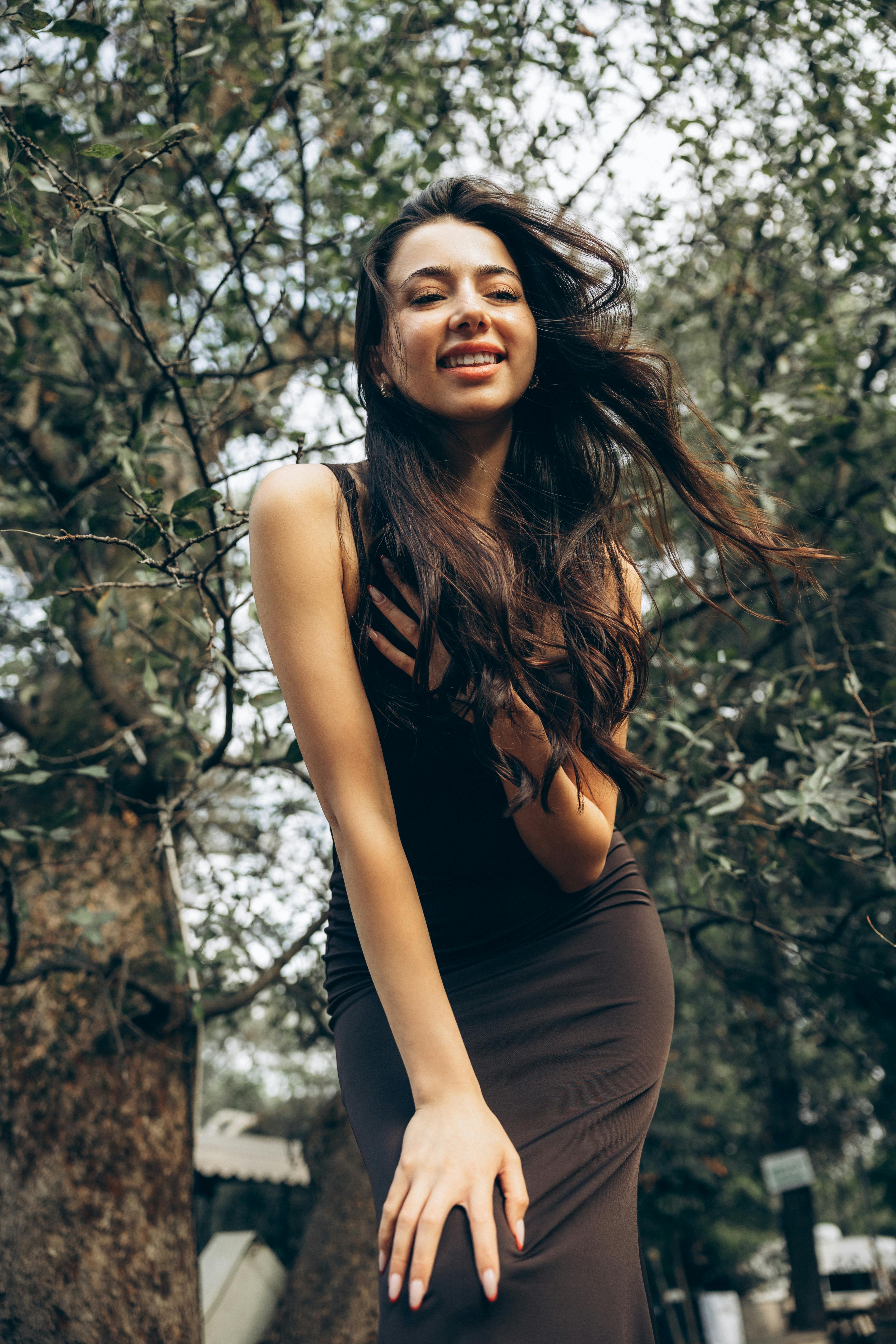 Women Style. Fashion Girl In Long Black Dress Posing Outdoors. Portrait Of  Beautiful Fashionable Female Model In Glamourous Evening Dress With Elegant  Hairstyle Posing Outdoors. High Quality Image. Stock Photo, Picture and