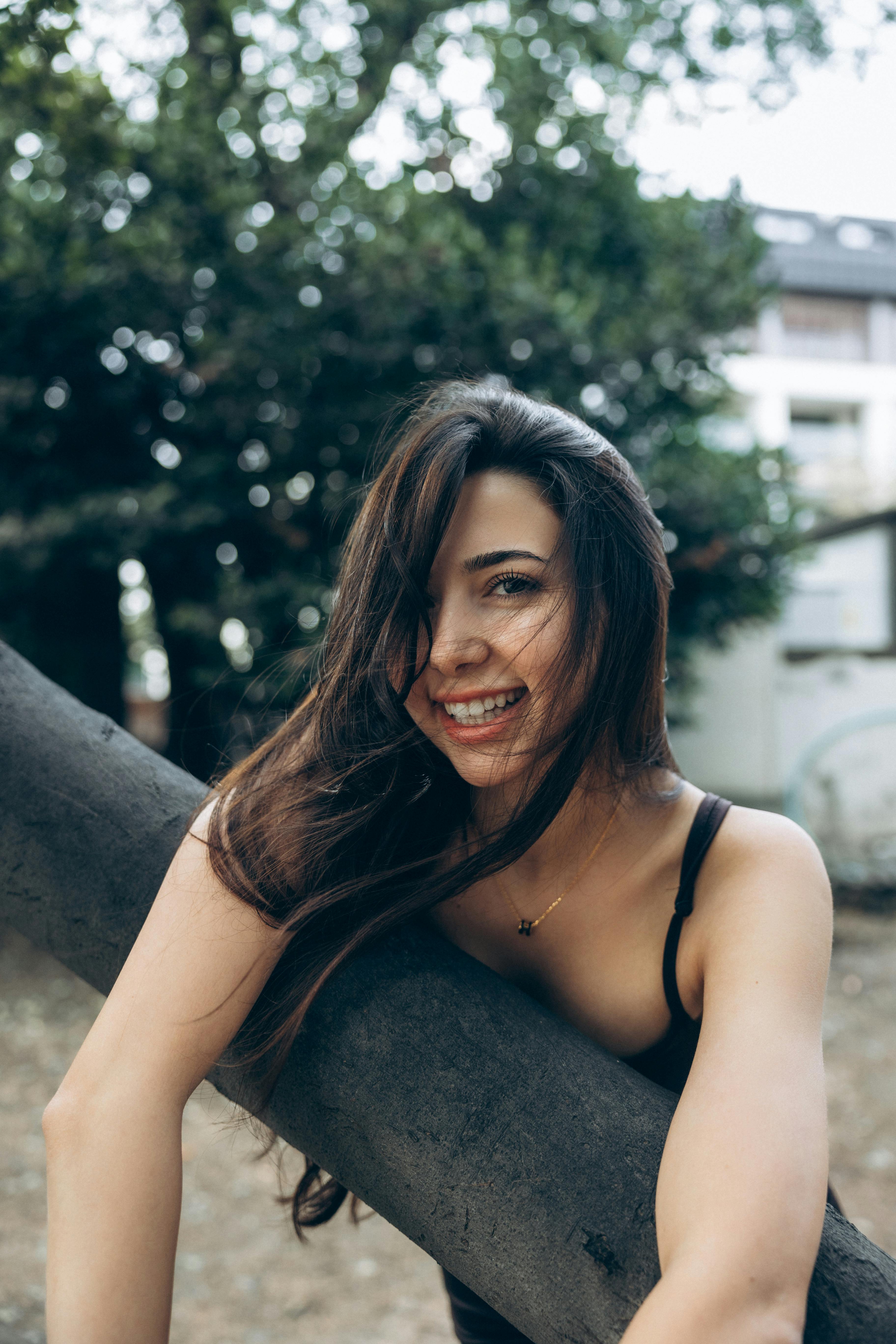 a woman smiling while leaning on a tree